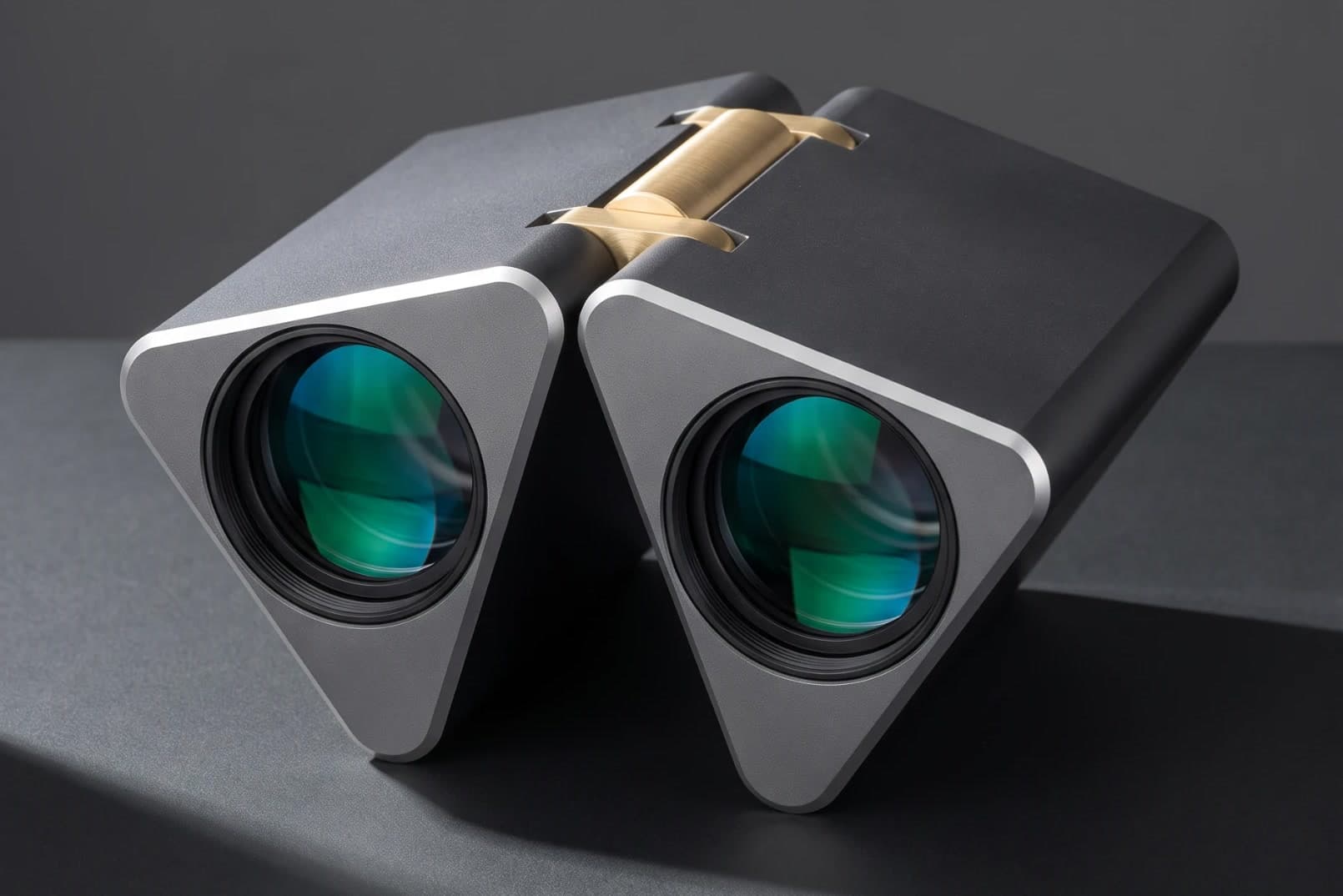 Prism Binoculars resting on a dark surface, two triangular metal halves joined by a brass hinge with a knurled focus dial between them
